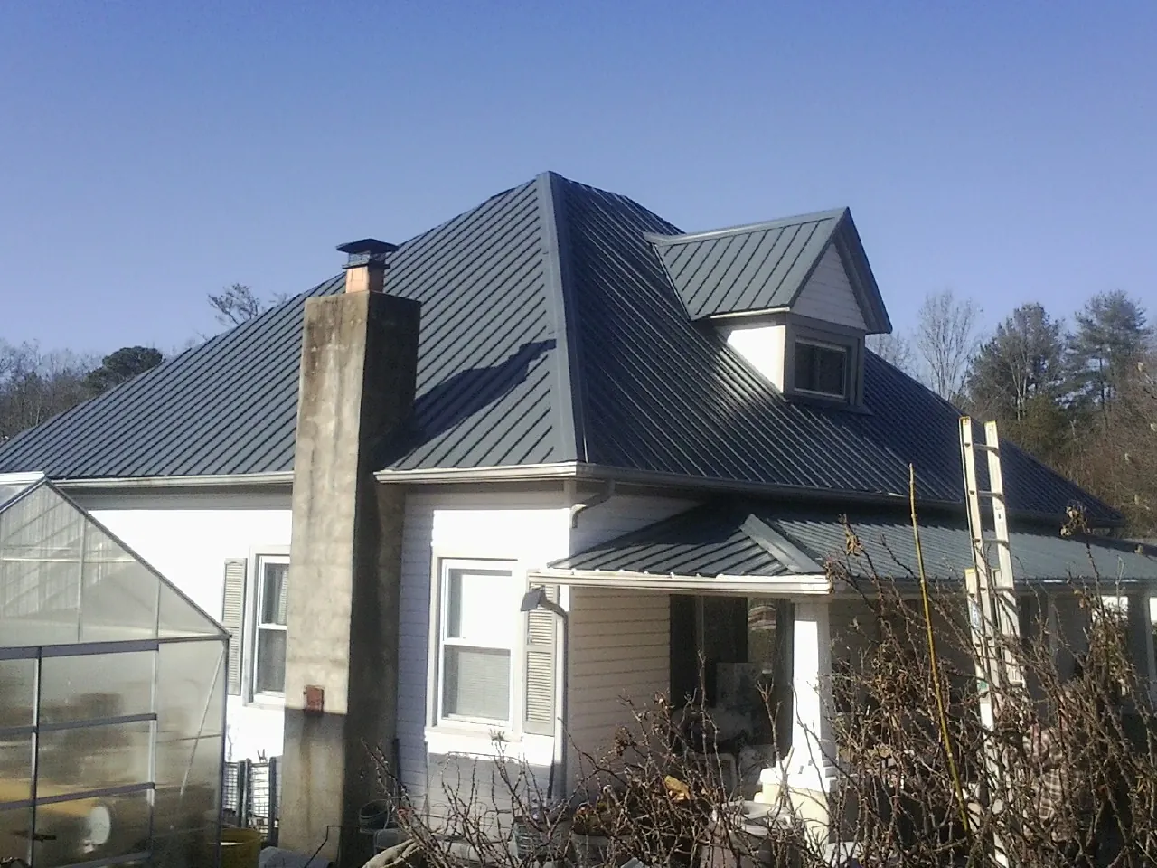 Dark blue standing seam metal roof on a white farmhouse with dormer — Slate & Tile Roof Repair by Roofing Brothers in Starrucca