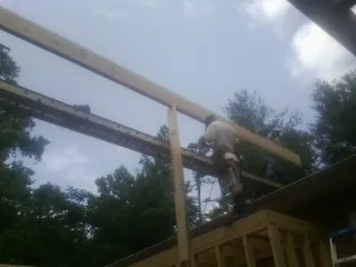 Carpenter setting a ridge beam over a new addition frame — Ice Dam Removal by Roofing Brothers in Starrucca