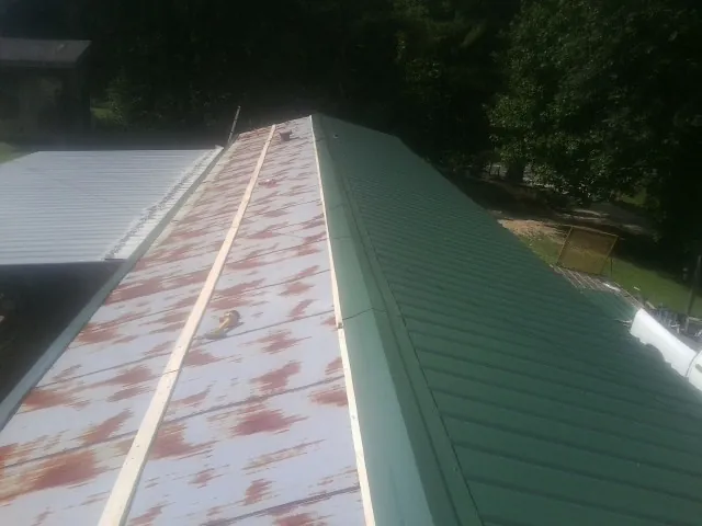 Old rusted panels beside newly installed green metal roofing — Wind Damage Roof Repair by Roofing Brothers in Starrucca