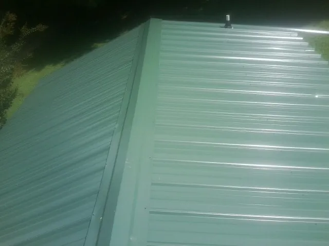 New green metal panels meeting at the ridge of a roof — Flat Roof Repair work by our crew in Starrucca