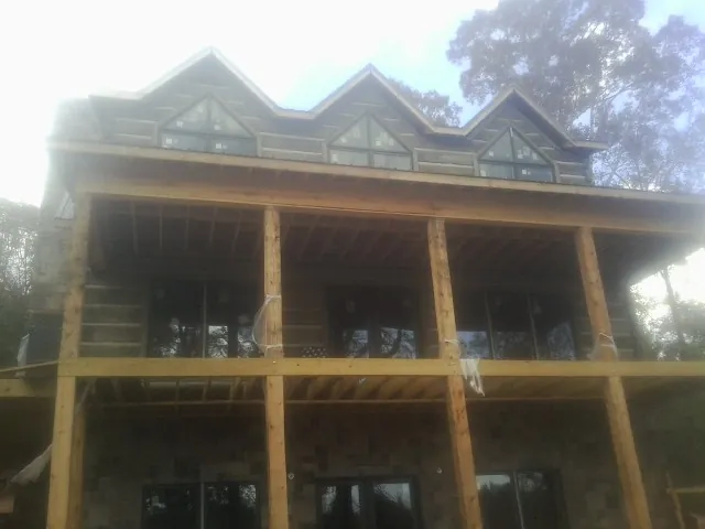 Dormers and porch framing on a large log home under construction — Roof Coating work by our crew in Starrucca