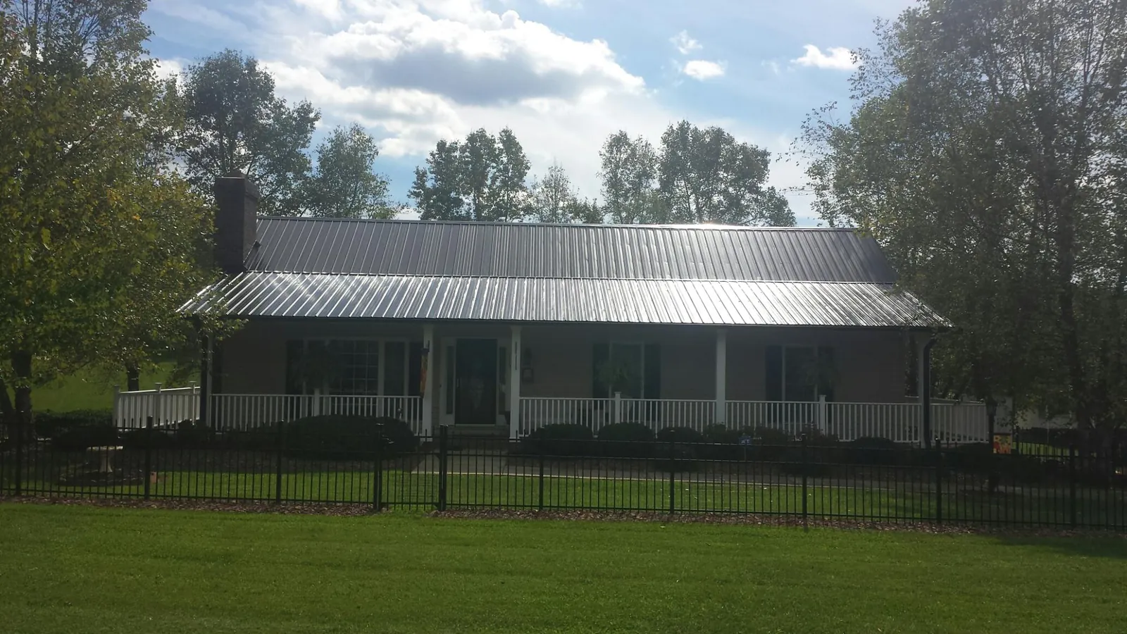 Gray metal roof on a brick ranch with a full width front porch — Gutter Guard Installation work by our crew in Starrucca