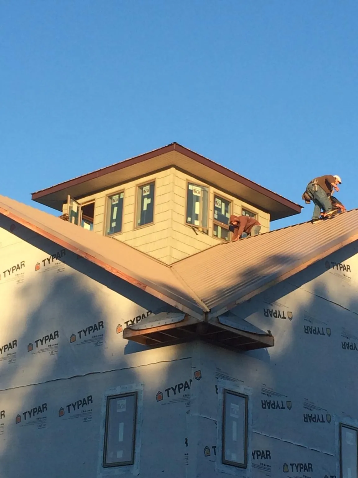 Roofers working around a rooftop cupola on a new metal roof at sunset — Roof Waterproofing in Starrucca by Roofing Brothers